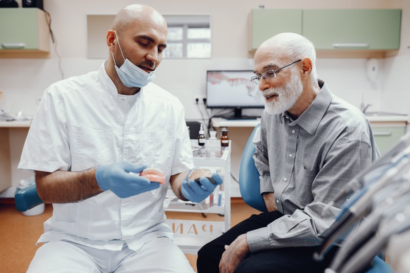  Patient reviewing denture and implant options with dentist