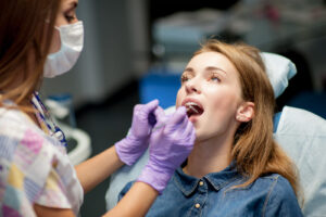 Dentist examining a woman’s teeth in a dental chair