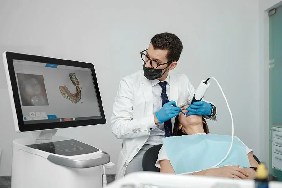 Male orthodontist using a 3D intraoral scanner on a patient's teeth.